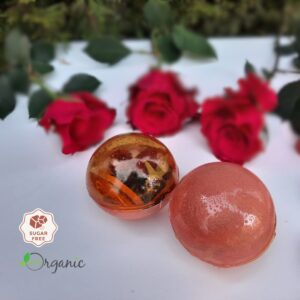 Tea sphere with vibrant fruit filling, styled with fresh roses and greenery for a luxurious presentation